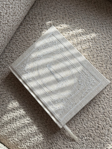 Lighthouse Embroidered Linen Planner sitting on chair 